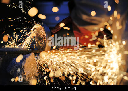 Worker cutting metal avec une meuleuse. Tandis que le broyage de Sparks Banque D'Images