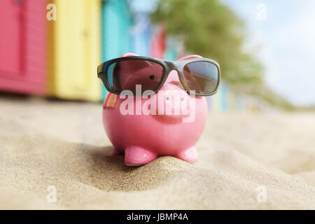 Tirelire sur le sable de la plage avec des lunettes de soleil et se baigner les cases Banque D'Images