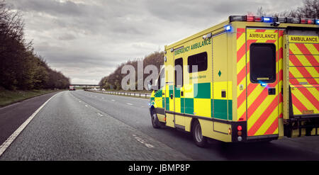 Ambulance en cas d'intervention d'urgence dans de mauvaises conditions météorologiques dangereuses conditions de conduite sur une autoroute au Royaume-Uni Banque D'Images