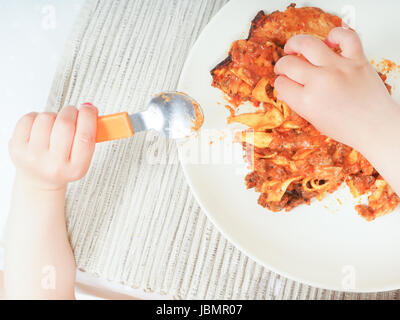 Un enfant bénéficiant d'une plaque de lasagne au dîner Banque D'Images