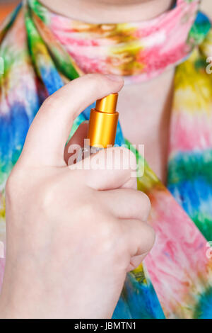 Girl spraying perfume sur foulard en soie de l'atomizer close up Banque D'Images