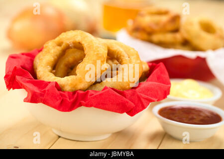 La bière fait maison fraîchement préparé-battered onion rings dans un bol avec des trempettes avec serviette sur le côté (Selective Focus, se concentrer sur l'avant de l'anneau de l'oignon sur la droite) Banque D'Images