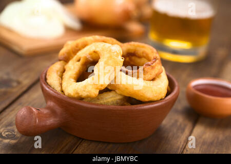 La bière fait maison fraîchement préparé-battered onion rings dans un bol avec du ketchup sur le côté (Selective Focus, se concentrer sur l'avant de l'anneau de l'oignon sur la droite) Banque D'Images