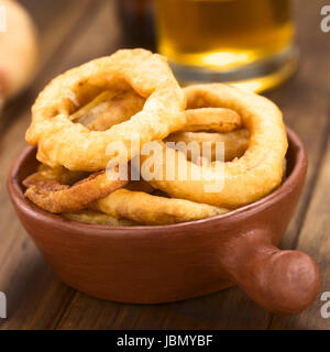 La bière fait maison fraîchement préparé-battered onion rings dans un bol avec de la bière dans le dos (Selective Focus, se concentrer sur l'avant de l'oignon sur le dessus) Banque D'Images