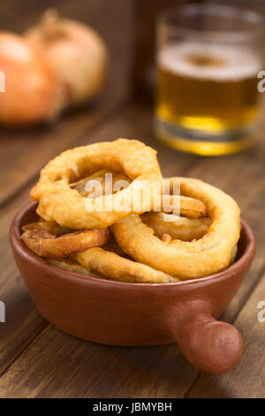 La bière fait maison fraîchement préparé-battered onion rings dans un bol avec de la bière dans le dos (Selective Focus, se concentrer sur l'avant de l'oignon sur le dessus) Banque D'Images