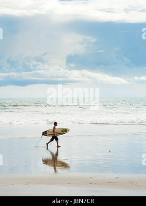 L'ÎLE DE BALI, INDONÉSIE - Mars 16, 2013 : garçon marcher avec un surf sur la plage. Bali est l'un des top des destinations monde de surf. Banque D'Images