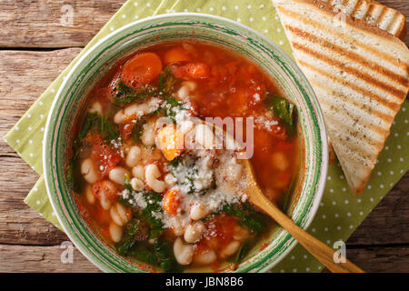 Soupe de haricots blancs avec les tomates, les épinards, les carottes et le parmesan sur la table horizontale vue du dessus. Banque D'Images