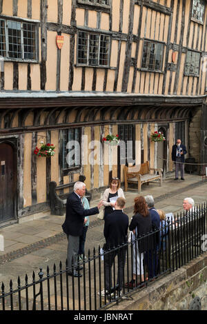 Frères / frère (un ancien résident) Ex-Serviceman mène / guides un groupe de touristes autour de l'hôpital de Lord Leycester. Warwick England UK Banque D'Images