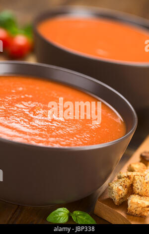 Soupe de tomates fraîches faites maison en bois foncé marron bols sur croûtons avec aliments complets sur le côté (Selective Focus Focus, un tiers dans la soupe) Banque D'Images