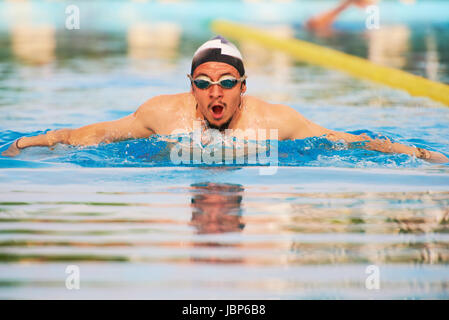 Homme actif swimming in pool avec style papillon Banque D'Images