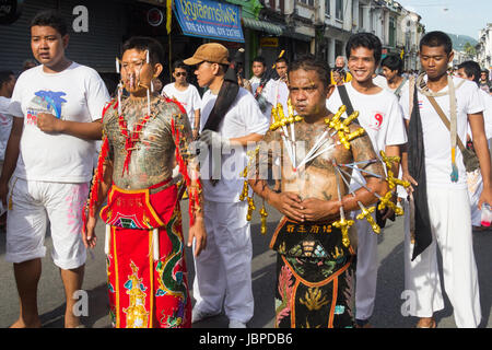 Les hommes avec le visage et le corps percé par des brochettes et des menottes à un défilé pendant les neuf dieux empereur festival (festival végétarien) à Phuket, Thaïlande Banque D'Images