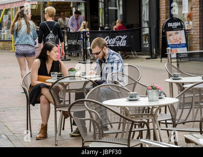 Un mixed race couple s'asseoir à une table à l'extérieur d'un café dans la rue Peascod à Windsor, Royaume-Uni. Banque D'Images