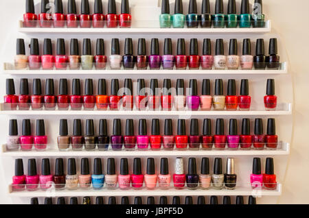 Etagères holding rangées de bouteilles de vernis à ongles dans un salon de manucure. Banque D'Images