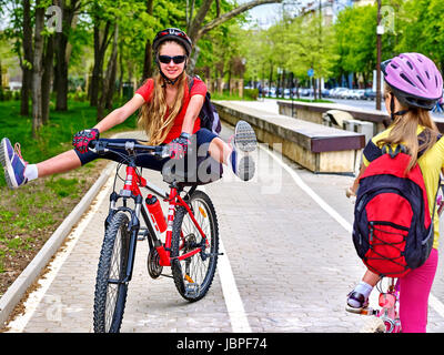 Chemin de bicyclette avec des enfants en ville. Le port de casque avec sac à dos filles ciclyng ride. Les enfants sur la voie cyclable blanc . Alternative aux transports urbains. Oncomin Banque D'Images