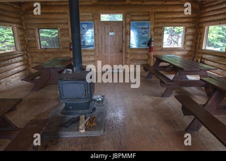 Intérieur de la cabine en rondins du abri Hargreaves, banc de pique-nique ou bancs et four à bois. Terrain de camping du sentier de randonnée du lac Berg, Colombie-Britannique Canada Banque D'Images