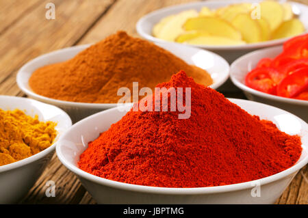 Bols de curry en poudre, le paprika, la cannelle moulue, tranches de racine de gingembre et piment rouge Banque D'Images