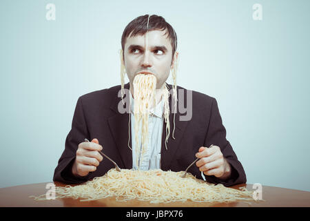 La suralimentation et le consumérisme concept. Silly nasty businessman eating pasta. Banque D'Images