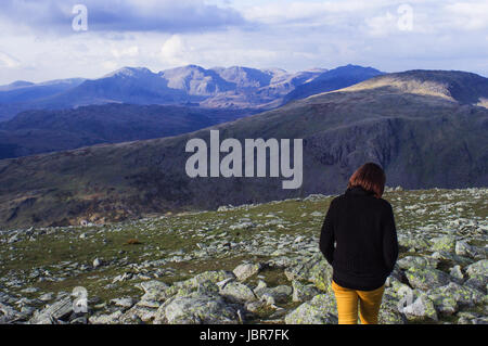 Une femme marche randonnée seul dans le Lake District, en Angleterre. Montagnes du Lake district peut être vu dans l'arrière-plan. Le crépuscule tombe sur les montagnes. Banque D'Images
