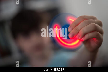 Hanovre, Allemagne. Le 08 juin, 2017. Un garçon est titulaire d'une filature Fidget Spinner dans sa main à Hanovre, Allemagne, 08 juin 2017. En raison de la longue durée d'exposition la LED ne s'allume que des bandes. Les disques avec un roulement à billes dans le centre travaillent tout à fait simple. Middlefinger et prise de pouce au centre et le trigger finger tourne. Photo : Silas Stein/dpa/Alamy Live News Banque D'Images