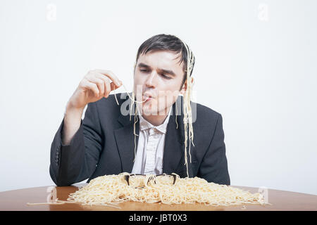 L'indulgence et le consumérisme concept. Gourmandise businessman eating pasta. Banque D'Images