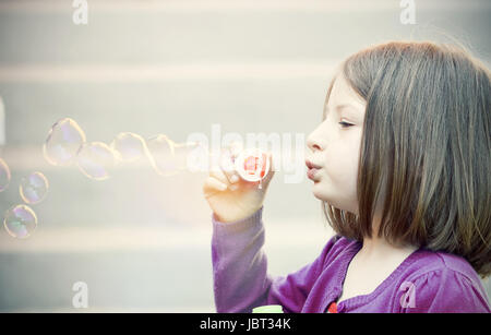 Style rétro photo de jeune fille soufflant des bulles de savon Banque D'Images