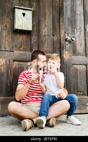 Jeune père et son petit-fils la consommation de crème glacée. Journée ensoleillée. Banque D'Images