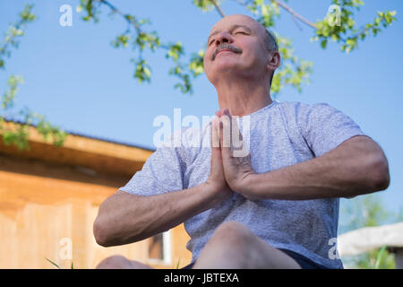 Senior man with moustache avec namaste assis.Concept de calme et de méditation. Banque D'Images