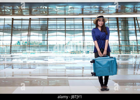 Smiling asian woman traveller avec hat transport des bagages sur la borne Airport Banque D'Images