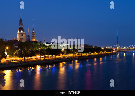 Skyline de Riga vu de l'autre côté de la rivière Daugava après le coucher du soleil. Trois tours d'église dans l'image sont le dôme de la cathédrale de Riga, l'église Saint-Sauveur et l'église Saint Pierre. Sur la droite est pont de chemin de fer et tour de diffusion Banque D'Images