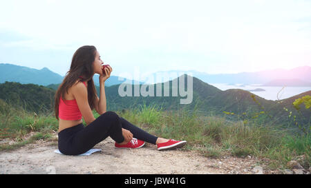 Runner femme manger apple sur sommet de montagne Banque D'Images