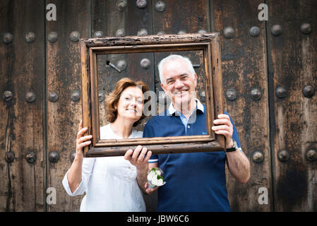 Portrait of senior couple holding, cadre en bois en face de leurs visages, Mexico, Mexique Banque D'Images