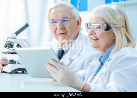 Smiling senior les scientifiques travaillant avec tablette numérique et microscope Banque D'Images