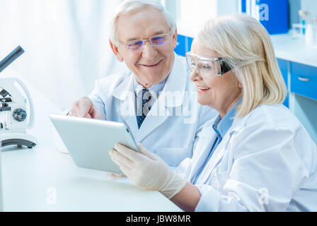 Smiling senior les scientifiques travaillant avec digital tablet in lab Banque D'Images