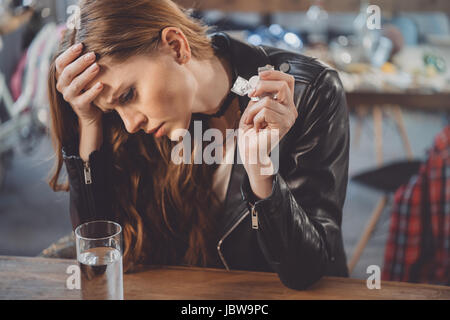 Femme avec gueule de bois avec des médicaments dans la chambre en désordre après partie Banque D'Images