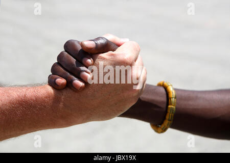 Poignée de main entre un Blanc et un Africain sur fond gris Banque D'Images