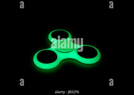 Dans le noir brillant Vert fidget spinner sur fond noir Banque D'Images