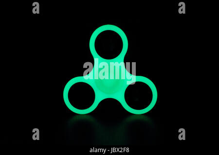 Dans le noir brillant Vert fidget spinner sur fond noir Banque D'Images