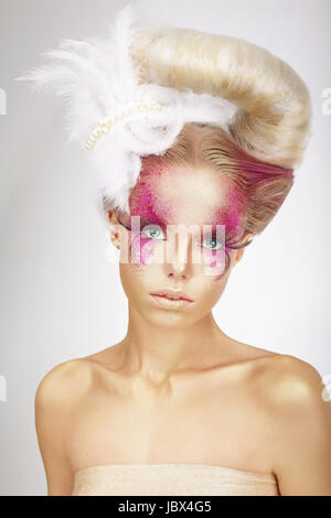 Faceart. Blonde avec la peau Rose, faux cils et plume blanche Banque D'Images