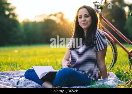 Woman Reading book on grass Banque D'Images