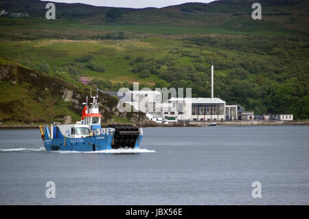 Le Jura à Islay (ferry) Dhiura Eilean arrivant à Feolin avec la distillerie de whisky Caol Ila en arrière-plan. Isle of Jura, îles écossaises. Banque D'Images