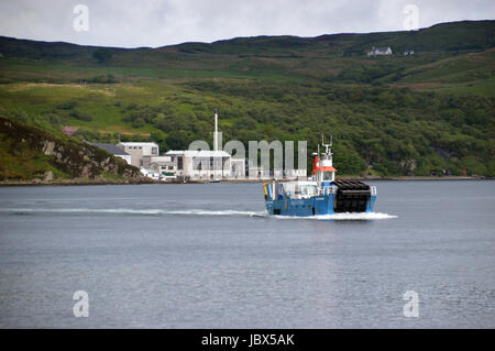 Le Jura à Islay (ferry) Dhiura Eilean arrivant à Feolin avec la distillerie de whisky Caol Ila en arrière-plan. Isle of Jura, îles écossaises. Banque D'Images