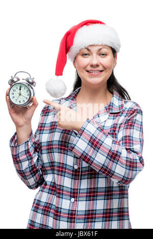 Jeune fille en pyjama à santa hat affiche l'heure de minuit, réveil Banque D'Images