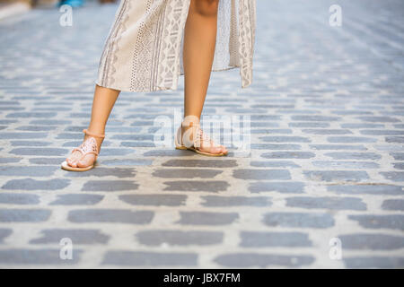 Pieds de femme portaient des sandales debout sur la rue pavée Banque D'Images