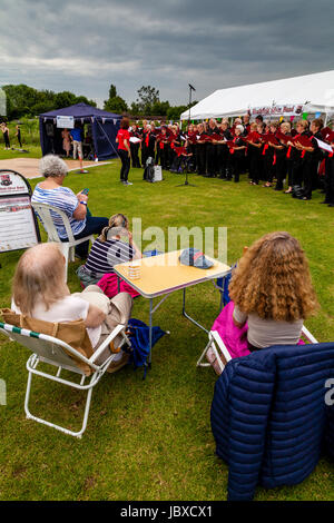 Les gens regarder une chorale communautaire chanter sous la pluie à la fête, Maresfield Maresfield, East Sussex, UK Banque D'Images