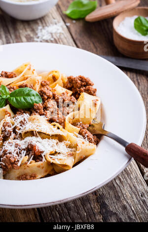 Pappardelle pâtes italiennes maison traditionnelle bolognese servi avec fromage Grana Padana sur table en bois rustique Banque D'Images