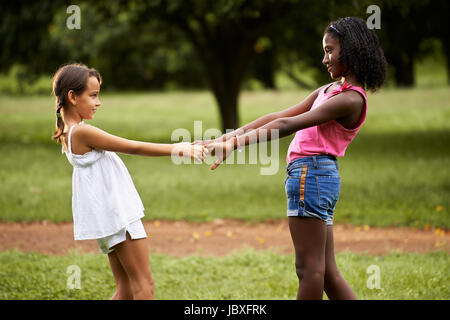 Deux petites filles hispaniques et africains jouant dans le parc public et tenir la main Banque D'Images