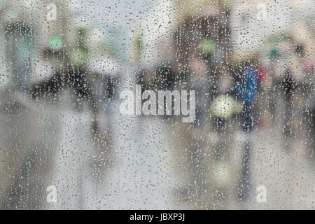 Gouttes de pluie sur les vitres, les gens à pied sur route dans la région de Rainy day, blurred motion abstract background. Concept de shopping, marche à pied, le mode de vie. Un espace réservé au texte Banque D'Images