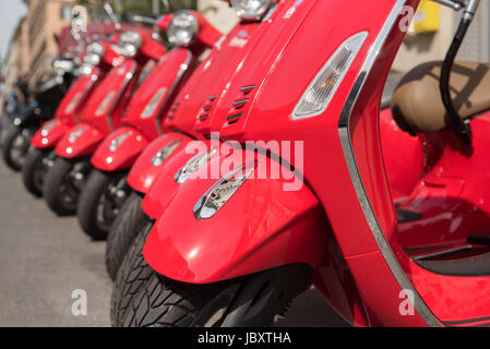 Beaucoup de style italien Vespa rouge moderne dans une rangée de motos garées dans la rue, selective focus détail Banque D'Images