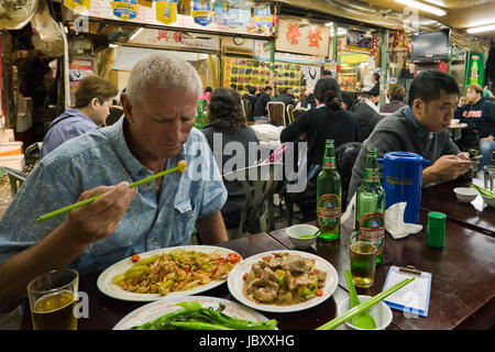 Vue horizontale à l'intérieur d'un restaurant animé de streetfood à Hong Kong, Chine. Banque D'Images