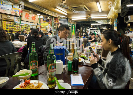 Vue horizontale à l'intérieur d'un restaurant animé de streetfood à Hong Kong, Chine. Banque D'Images